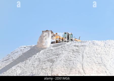 Huelva, Spanien - 1. Oktober 2020: Bagger arbeiten in einem riesigen Pfahlsalz in der Saline in Marismas del Odiel. Meersalz, das durch die Verdunstung von hergestellt wird Stockfoto