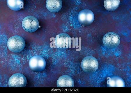 Gefrostete und glänzende Weihnachtskugeln liegen auf einem blauen Betonhintergrund. Urlaub Hintergrund, Draufsicht. Stockfoto