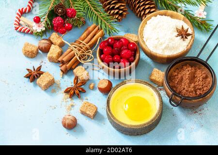 Saisonaler Backwinter. Zutaten für das Weihnachtsbacken - Kakao, Preiselbeeren, Gewürze, Nüsse, Mehl und Eier auf blauem Steingrund. Stockfoto