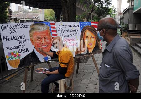 Ein Mann sieht einem Künstler zu, der Plakate von US-Präsident Donald Trump und First Lady Melania Trump malt.Präsident Donald Trump und First Lady Melania haben vor der Präsidentschaftswahl positiv auf das Coronavirus getestet. Stockfoto