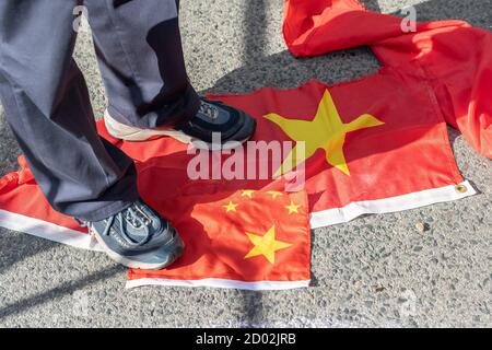 Ein Mann aus Hongkong tritt bei einem Protest gegen die kommunistische Regierung zum 71. Jahrestag der kommunistischen Nation auf zerrissene chinesische Fahnen. Stockfoto