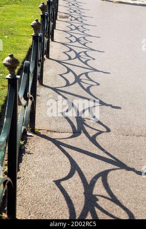 Bournemouth, Dorset, England, 15. September 2020, Alte kunstvolle Metallgeländer werfen einen starken Schatten auf den Bürgersteig. Stockfoto