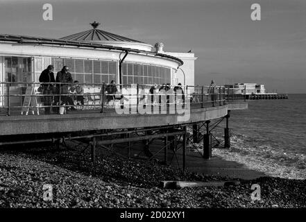 AJAXNETPHOTO. WORTHING, ENGLAND. - LIDO TERRASSE - LEUTE GENIESSEN EIN BISSCHEN WINTERSONNE AUF DER LIDO CAFÉ TERRASSE; WORTHING PIER SICHTBAR DARÜBER HINAUS. FOTO: JONATHAN EASTLAND/AJAX REF:81201 2 Stockfoto