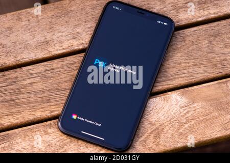 Tallinn / Estland - 28. September 2020: Schwarzes iphone mit Logo von Adobe photoshop auf dem Bildschirm. Holzhintergrund. Kann als Veranschaulichung für ma verwendet werden Stockfoto