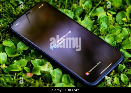 Tallinn / Estland - 28. September 2020: Schwarzes iphone mit Logo von Adobe photoshop auf dem Bildschirm. Grünes Gras Hintergrund. Kann als illustrative f verwendet werden Stockfoto