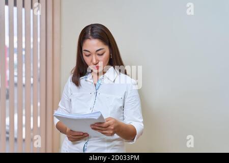 Asiatische Frau Arzt im weißen Mantel liest medizinische Dokumente Stockfoto