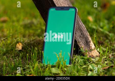 Tallinn / Estland - 28. September 2020: Schwarzes iphone mit Logo der Bolt-Anwendung auf dem Bildschirm. Grünes Gras Hintergrund. Kann als Veranschaulichung verwendet werden Stockfoto
