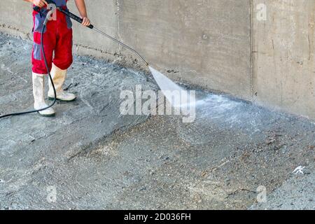 Reinigung von schmutzigem Beton im Freien mit Hochdruckwasserstrahl. Stockfoto