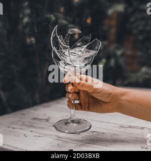 Zerbrochener Kristallkelch in der Hand einer Frau Stockfoto