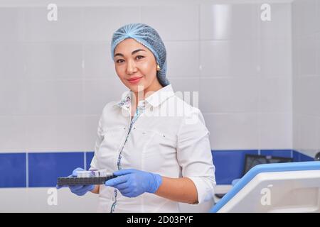 Asiatische Frauenärztin in einem weißen Mantel mit Tests Stockfoto