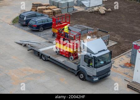 Zwei rote Hebebühnen werden auf einen LKW verladen Wegtransportiert werden Stockfoto