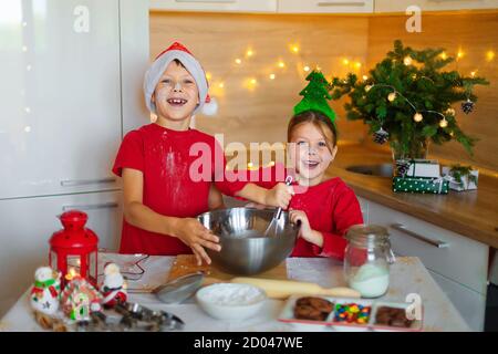 Glückliche Kinder bereiten am Vorabend des neuen Jahres Lebkuchen zu. Junge und Mädchen in der Küche warten auf Weihnachten. Kinder machen Urlaub Cookies zu Hause. Stockfoto