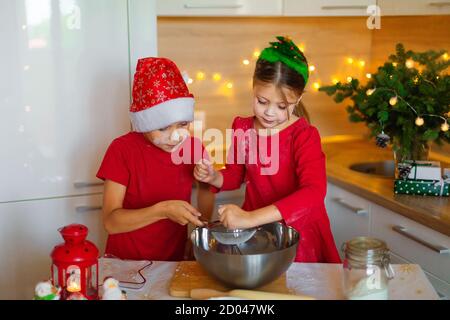 Glückliche Kinder bereiten am Vorabend des neuen Jahres Lebkuchen zu. Junge und Mädchen in der Küche warten auf Weihnachten. Kinder machen Urlaub Cookies zu Hause. Stockfoto