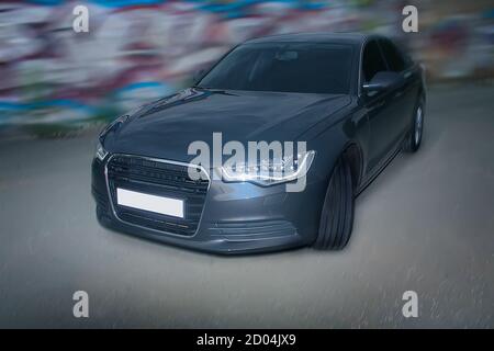 Dunkles Auto an der Wand mit Graffiti Stockfoto