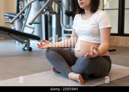 Aktive schwangere Frau Übung im Fitnesscenter im Yogaraum. Die junge Mutter mit Baby erwartet bei schwangeren Bauch. Mutterschaft pränatale Versorgung und Stockfoto