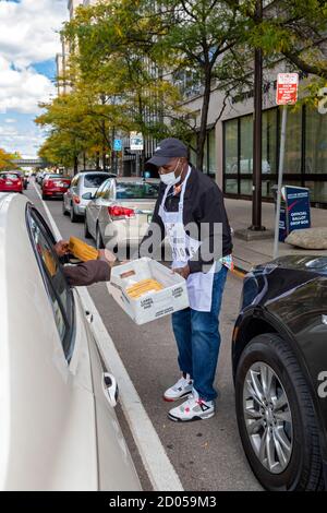 Detroit, Michigan, USA. Oktober 2020. Ein Arbeiter für Detroits Wahlabteilung nimmt abwesende Stimmzettel für die November-Präsidentschaftswahl von einem stetigen Strom von Fahrern am Büro des Stadtbeamten an. Kredit: Jim West/Alamy Live Nachrichten Stockfoto