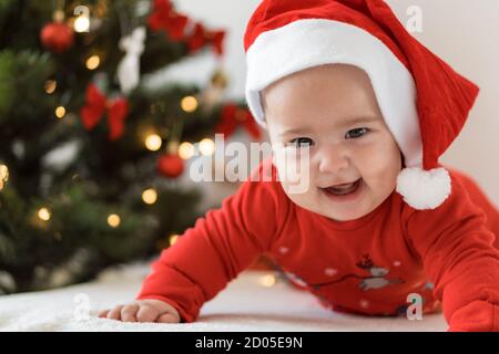 Weihnachten und glückliches neues Jahr, Säuglinge, Kindheit, Urlaub Konzept - close-up 6 Monate altes neugeborenes Baby in weihnachtsmann Hut auf seinem Bauch kriecht mit Stockfoto