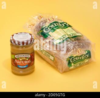 Arnold Country Klassiker Haferbraungebrot und Smuckers natürliche, cremige Erdnussbutter auf einem gelben Hintergrund fotografiert. Stockfoto