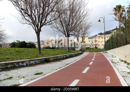 Fahrradweg ohne Menschen in einer grünen Gegend der Stadt Genua. Im Hintergrund die Gebäude des Viertels Pra. Stockfoto