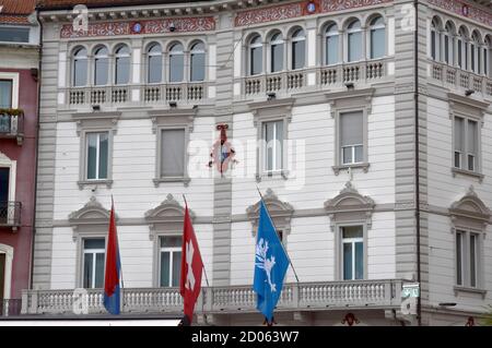 Das Rathaus von Locarno befindet sich in einem alten Palast namens Palazzo Marcacci auf Italienisch. Das Gebäude hat drei Fahnen an der Fassade, eine Schweizer, Stockfoto