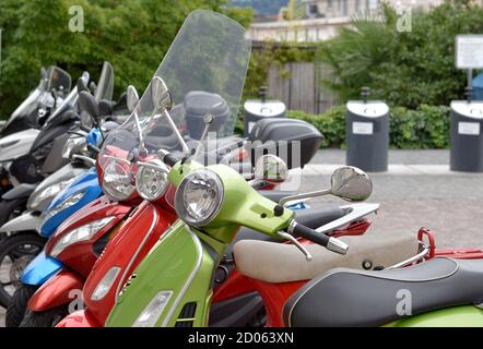 Detail der Mopeds verschiedener Farben in Reihe geparkt. Typisches Transportmittel in engen Gassen der Stadt Locarno im Tessin, einem italienischsprachigen Kanton Stockfoto