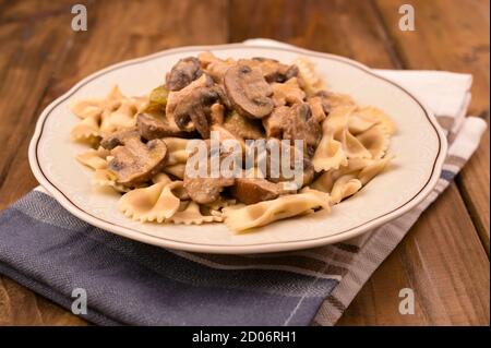 Butterfly Pasta mit Pilzen und Parmesan Sauce. Typisch italienische Küche aus dem Süden. Hochwertige Fotos. Speicherplatz kopieren. Stockfoto