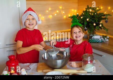 Glückliche Kinder bereiten am Vorabend des neuen Jahres Lebkuchen zu. Junge und Mädchen in der Küche warten auf Weihnachten. Kinder machen Urlaub Cookies zu Hause. Stockfoto