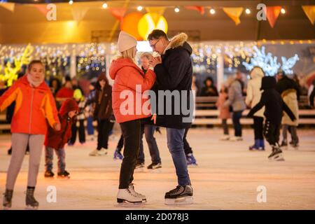 Gemeinsam Schlittschuhlaufen. Romantischer Winterurlaub in der Eisarena. Junges Paar Schlittschuhlaufen auf der Eisbahn. Das beste Weihnachten überhaupt. Winterspaß. Süßer Valentinstag Stockfoto