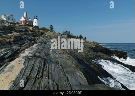 Wellen brechen entlang der felsigen Küste. Der Leuchtturm Pemaquid Point befindet sich auf der Spitze einzigartiger metamorphischer Felsformationen, die eine beliebte Attraktion sind. Stockfoto