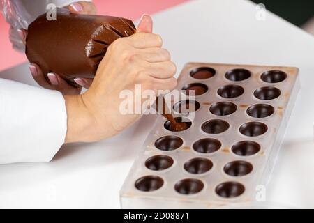 chocolatier Gießen Karamell Füllung in Schokoladenform Herstellung handgefertigten Süßigkeiten Stockfoto