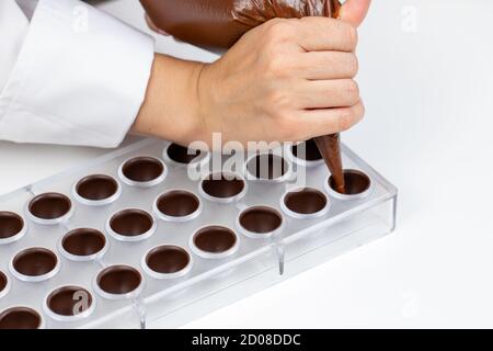 chocolatier Gießen Praline Füllung in Schokoladenform Vorbereitung belgien Süßigkeiten Stockfoto