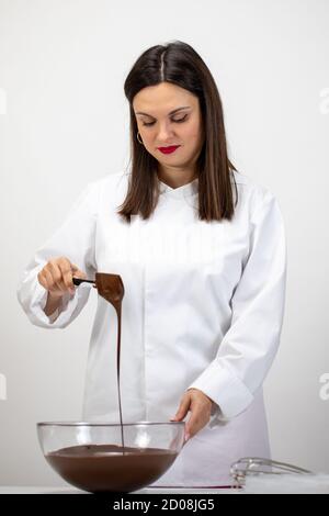 Schöne Konditor Gießen dunkle geschmolzene Schokolade, isoliert weißen Hintergrund Stockfoto