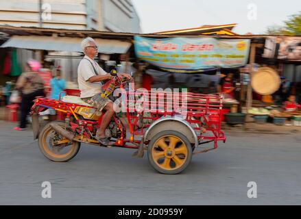 Sukhothai, Tahiland - 2019-03-06 - der alte Mann fährt mit seinem Dreirädrigen Motor Warenkorb durch den Markt. Stockfoto