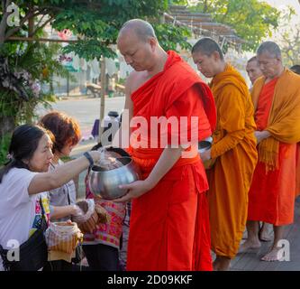 Lampeng, Tahiland - 2019-03-07-Linie der Mönche erhalten Geschenke von Nahrungsmitteln aus Anbeter entlang der Straße. Stockfoto