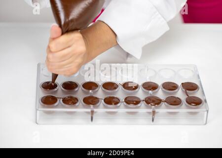 chocolatier Gießen geschmolzene Schokolade in Form Herstellung von handgefertigten Süßwaren Stockfoto