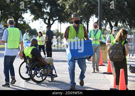 Austin, Texas, USA. Oktober 2020. Beamte von Travis County Elections sammeln Kisten mit Briefwahlstimmen, die von den Wählern persönlich fallen gelassen werden, wenn in Texas die Wahl für den umstrittenen Präsidentschaftswettbewerb sowie für andere Rennen beginnt. Kredit: Bob Daemmrich/Alamy Live Nachrichten Stockfoto