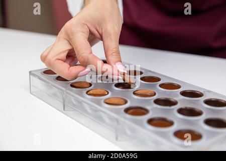 Konditor Hinzufügen von Mandeln in Karamell Füllung Schokoladenform Vorbereitung Süßigkeiten Stockfoto