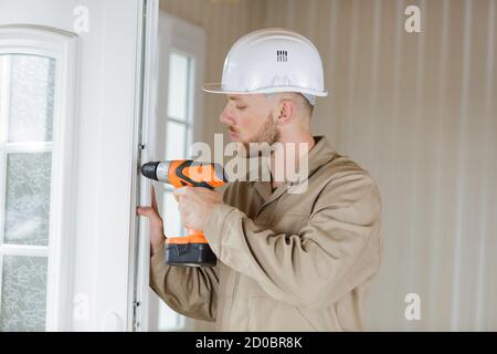 Männlicher Baumeister bohrt eine Tür Stockfoto