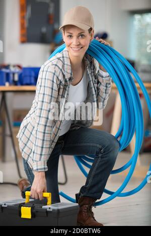 Lächelnd junge hübsche Frau mit Befestigung Rohr Problem Stockfoto