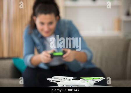 Junge Frau, die eine Drohne in Innenräumen betreibt Stockfoto
