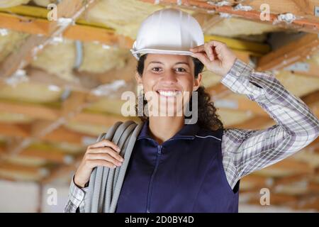 Weibliche Bauherrin kippt ihren Hardhut in Gruß Stockfoto