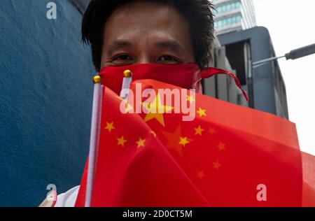 Ein pro-chinesischer Unterstützer verschenkt am 1. Oktober 2020 chinesische Flaggen und Ballons an Fußgänger in Hongkong, China. Die Polizei entsetzte 6,000 Beamte während des 71. Chinesischen Nationalfeiertags, um jeglichen illegalen Protesten und Versammlungen in Hongkong entgegenzuwirken. Stockfoto