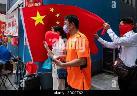 Ein pro-chinesischer Unterstützer verschenkt am 1. Oktober 2020 chinesische Flaggen und Ballons an Fußgänger in Hongkong, China. Die Polizei entsetzte 6,000 Beamte während des 71. Chinesischen Nationalfeiertags, um jeglichen illegalen Protesten und Versammlungen in Hongkong entgegenzuwirken. Stockfoto