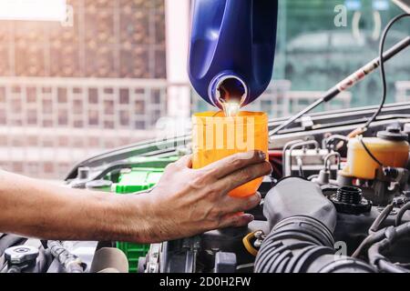 Auto-Mechaniker füllt das Motoröl des Autos innerhalb der Auto-Reparatur-Center, die Automobilindustrie und Garage Ideen. Stockfoto