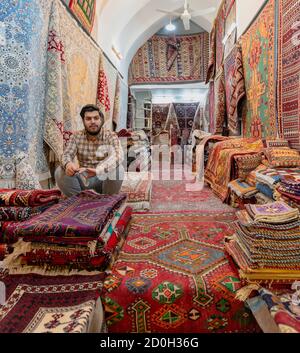 Shiraz, Iran - 2019-04-08-Mann sitzt in seinem Teppich Teppich speichern. Stockfoto