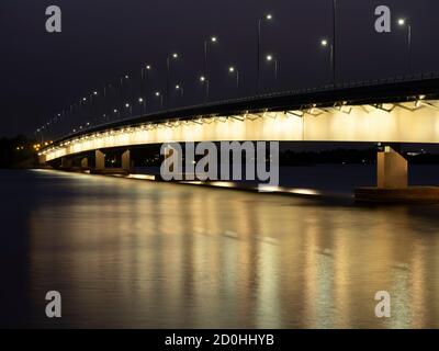 Helsinki/Finnland - 2. OKTOBER 2020: Eine wunderschöne nächtliche Stadtlandschaft einer beleuchteten Autobahnbrücke, die Spiegelungen auf dem Wasser wirft. Stockfoto