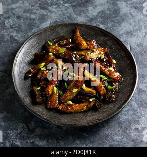 Nahaufnahme der Brut Bulgogi Aubergine auf Platte über dunklen Stein Hintergrund. Gebratene Aubergine im koreanischen Stil. Stockfoto