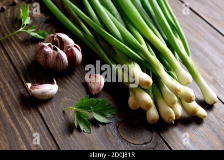 Frische grüne Zwiebel und Knoblauch auf Holzhintergrund. Nahaufnahme Stockfoto