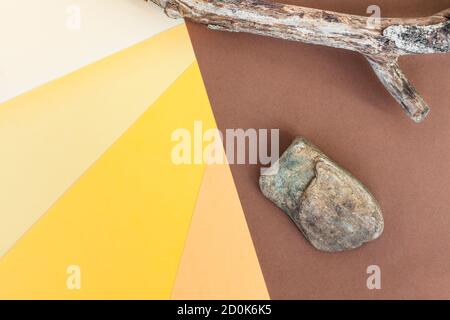 Abstrakt buntes Papier Hintergrund. Dunkelbrauner, beiger, oranger, gelber und heller Papierhintergrund. Stein und trockener Baum Zweig Stockfoto