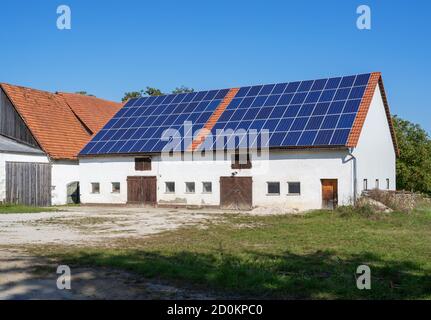 Grüner Energie mit Solarkollektoren auf dem Dach eines landwirtschaftlichen Gebäudes Stockfoto